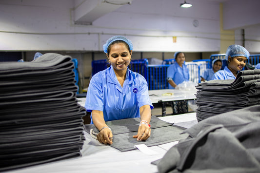 Factory workers folding clothes on a table.